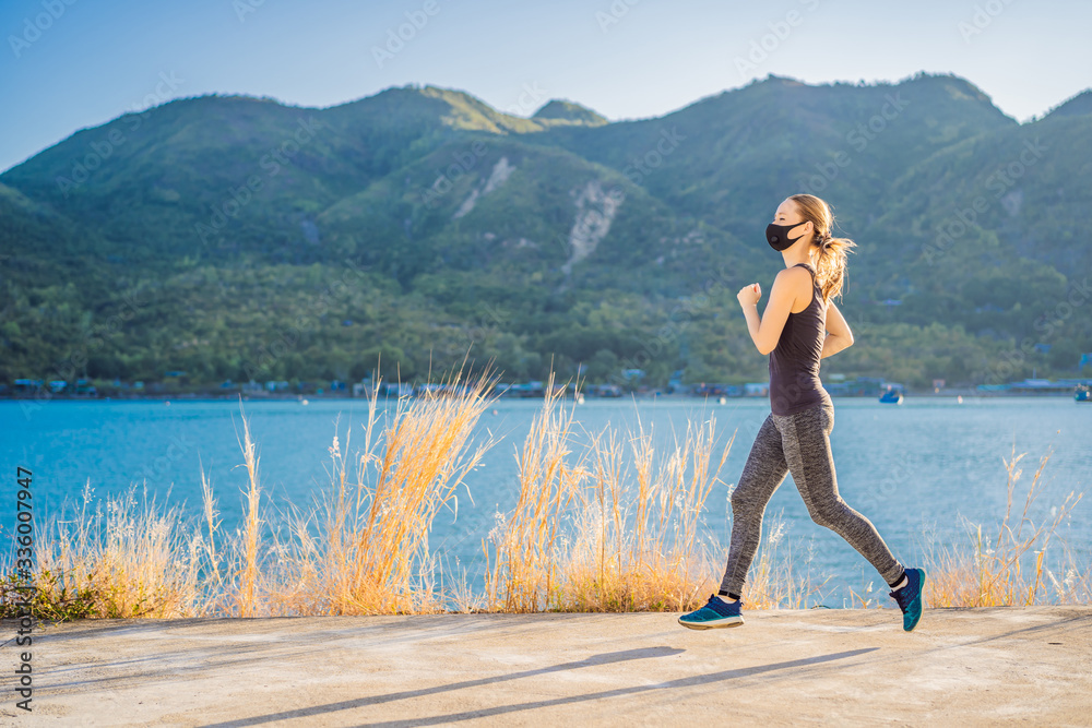 Fototapeta premium Runner wearing medical mask, Coronavirus pandemic Covid-19. Sport, Active life in quarantine surgical sterilizing face mask protection. Outdoor run on athletics track in Corona Outbreak. Keep your