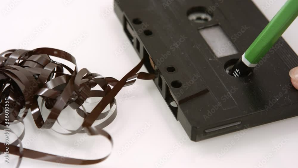 Rewinding a vintage stuck audio tape in an old worn cassette with a pencil. close up Stock ビデオ