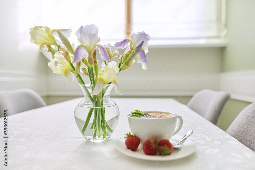 Strawberry tea on table, with vase of irises flowers Strawberry tea on table, with vase of irises flowers