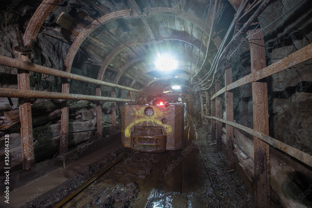 Naklejka premium Electric locomotive in underground gold mine shaft tunnel