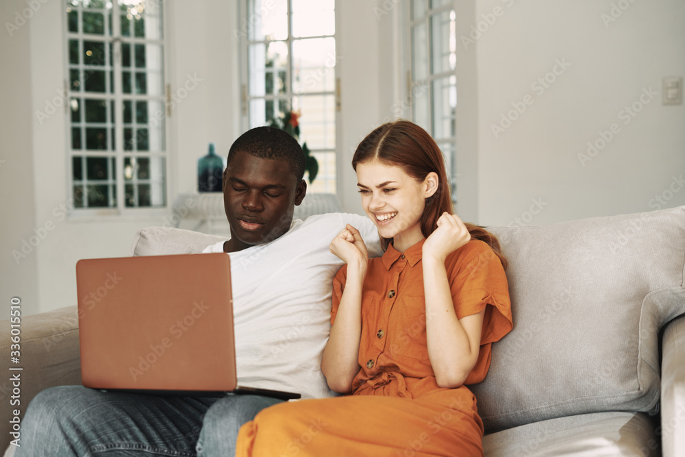 couple sitting on sofa with laptop