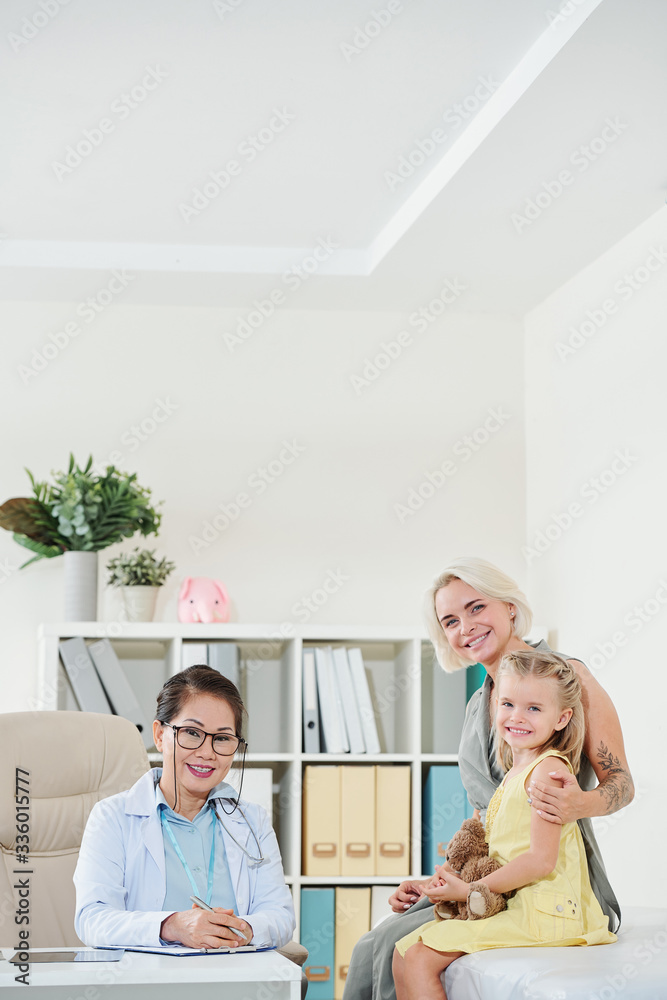 Happy smiling pretty woman and her little daughter in office of pediatrician Happy smiling pretty woman and her little daughter in office of pediatrician