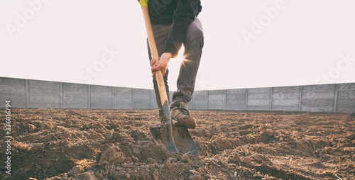 The man is digging the soil ground on his country house