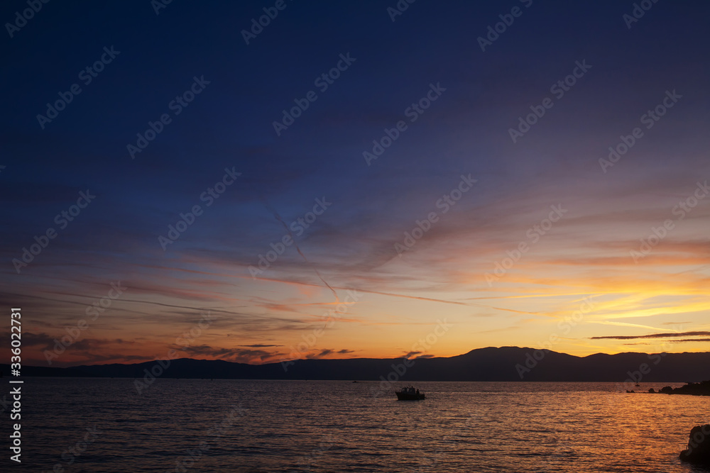 Silhouette of lonely boat in the sunset with dramatic sky. High seas sunset with a fishing ship on the horizon. Silhouette of lonely boat in the sunset with dramatic sky. High seas sunset with a fishing ship on the horizon.