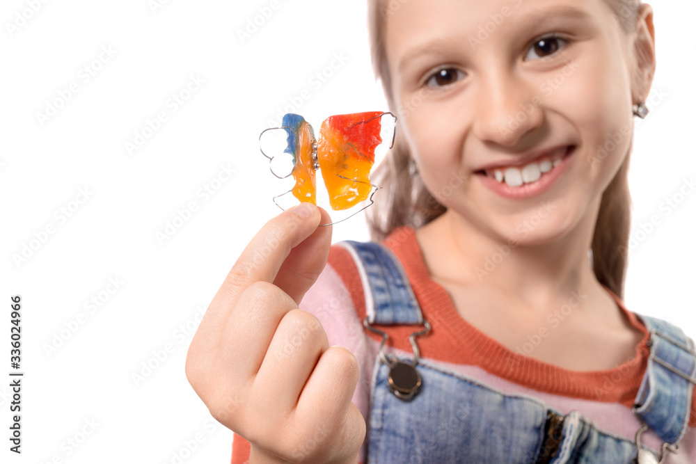 Little girl with orthodontics appliance isolated on white background.