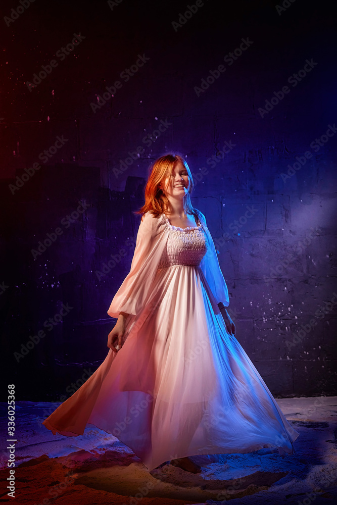 Pretty young sexy model female with blonde hair in amazing long white dress and posing in dark studio Pretty young sexy model female with blonde hair in amazing long white dress and posing in dark studio