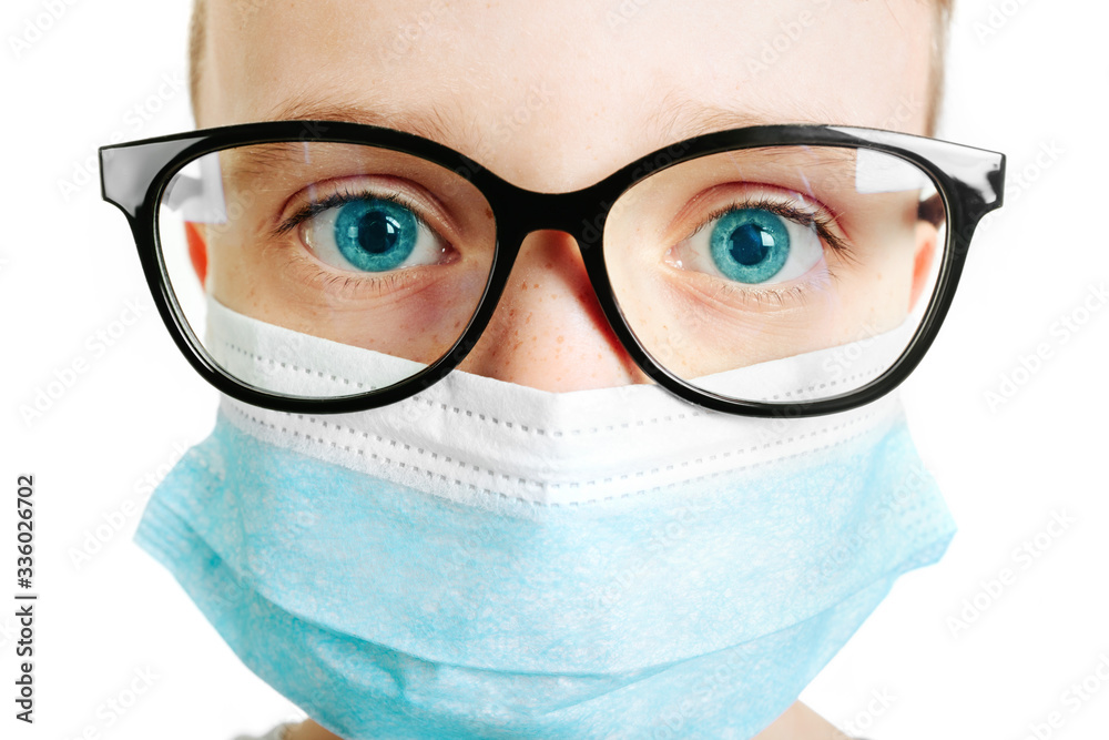 Face of a mask-wearing boy with fear in the eye Close-up on a white background.Coronavirus and Air pollution pm2.5 concept Face of a mask-wearing boy with fear in the eye Close-up on a white background.Coronavirus and Air pollution pm2.5 concept