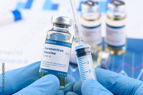 Coronavirus COVID-19 vaccine vial and injection syringe in scientist hands concept. Research for new novel corona virus immunization drug. photo