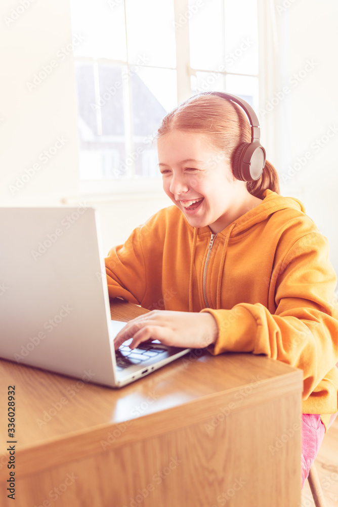 School age girl is home schooling using laptop during self isolation at her bedroom, online education, doing homework, distance learning School age girl is home schooling using laptop during self isolation at her bedroom, online education, doing homework, distance learning