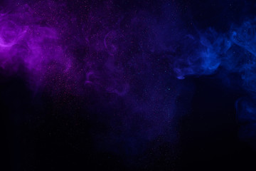 Colorful smoke fog clouds with shiny dust sparkles of glitter on black background