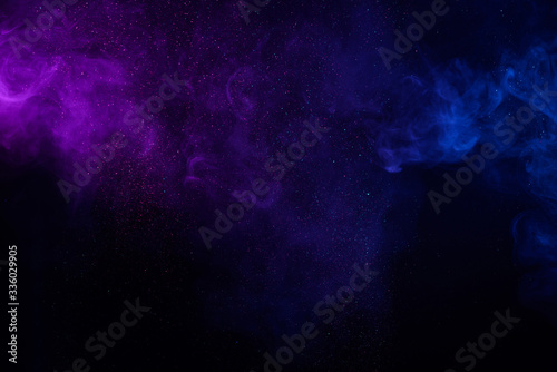 Colorful smoke fog clouds with shiny dust sparkles of glitter on black background