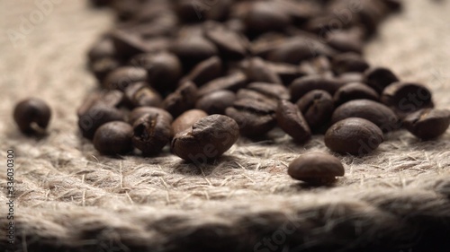 Beautiful brown roasted coffee beans lie on canvas table, camera flies over raw drink. Close up footage