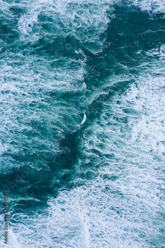 Blue foamy ocean waves and sand aerial drone top view