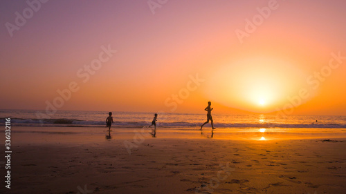 Fototapeta Naklejka Na Ścianę i Meble -  Father with kids playing in the beach at sunset