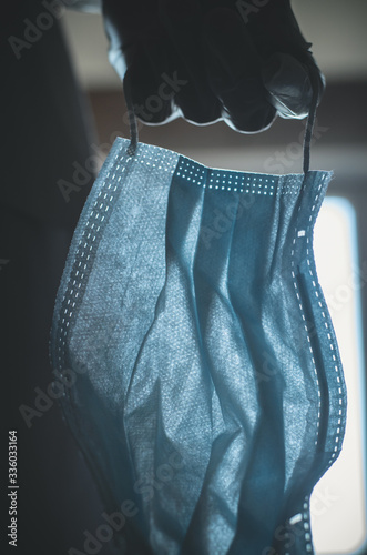 A medical virus protection face mask in a hand in a glove close-up