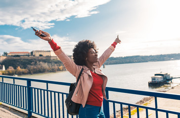 Young smiling african american girl walking through the city with her arms outstretched.
