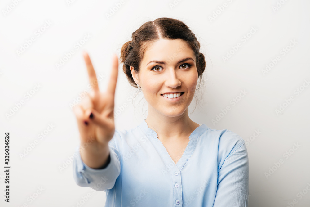 A woman shows a gesture of victory. Isolated on a white background A woman shows a gesture of victory. Isolated on a white background