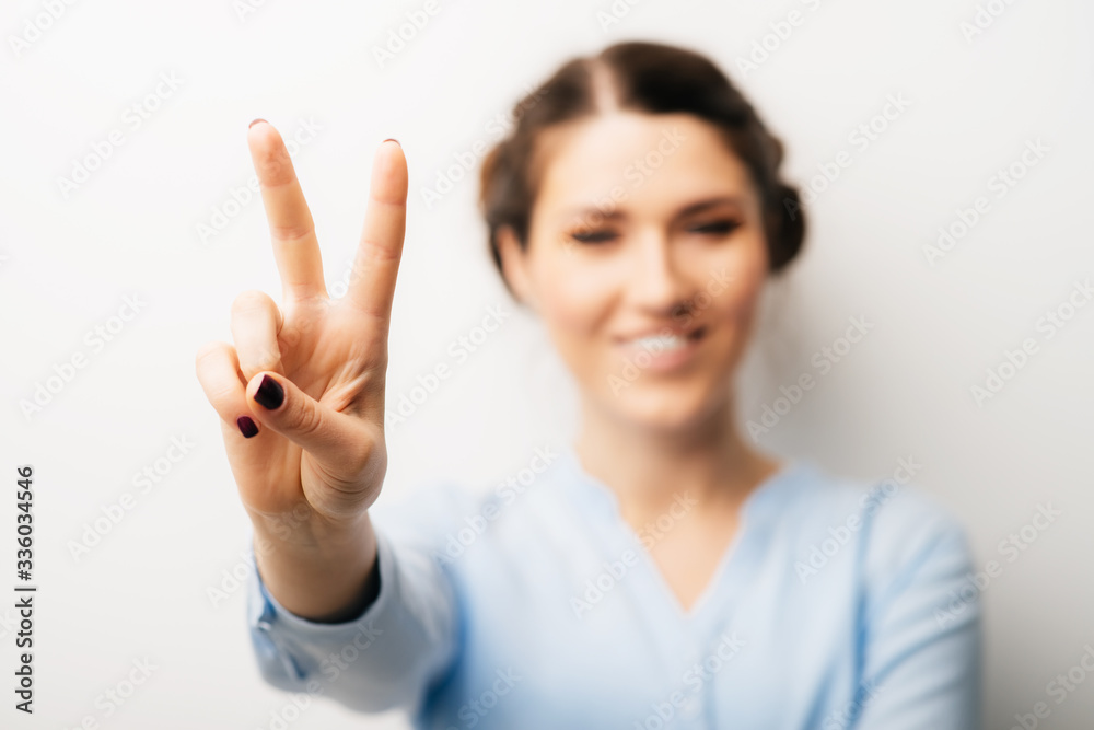 A woman shows a gesture of victory. Isolated on a white background A woman shows a gesture of victory. Isolated on a white background
