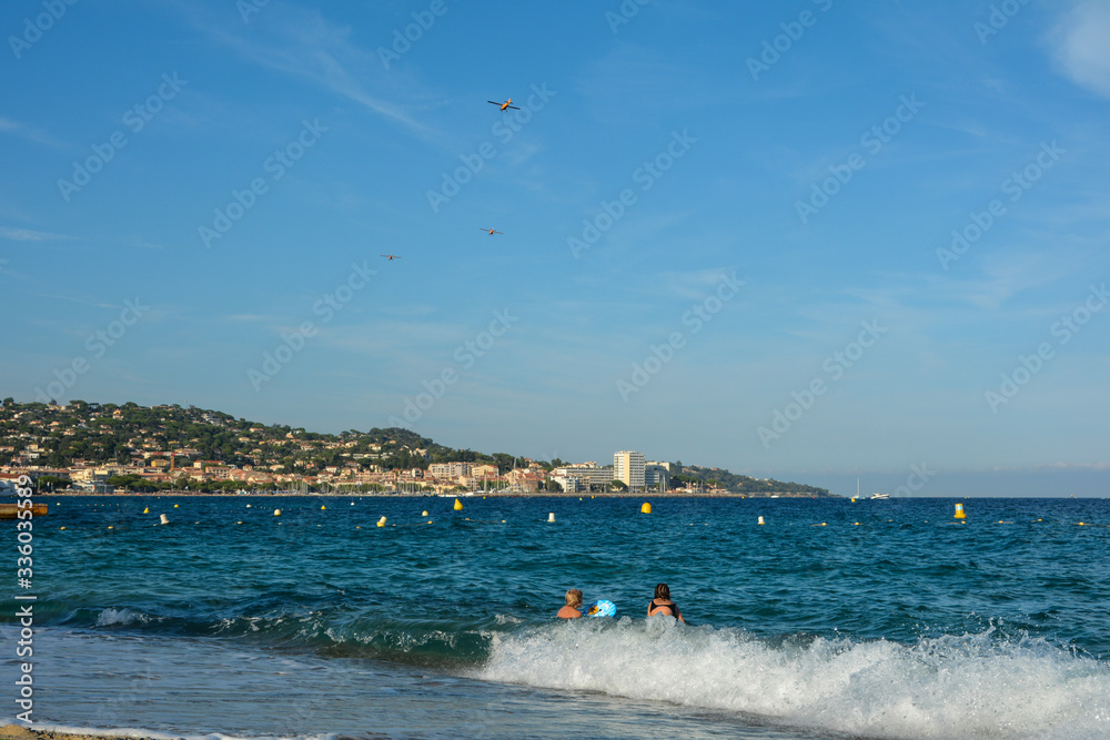 Children play in the French sea with Sainte-Maxime in the background