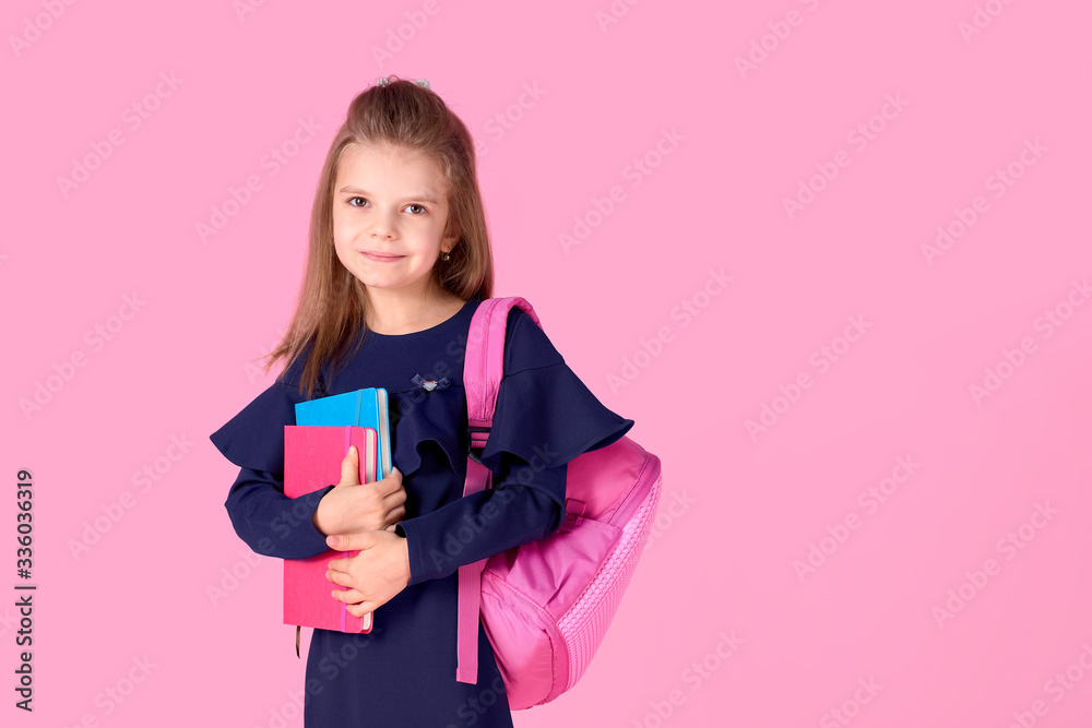 Back to school concept Half turned photo portrait of lovely confident beautiful clever girl with copybook notebook wearing school uniform dress pink bright backpack isolated. Back to school concept Half turned photo portrait of lovely confident beautiful clever girl with copybook notebook wearing school uniform dress pink bright backpack isolated.