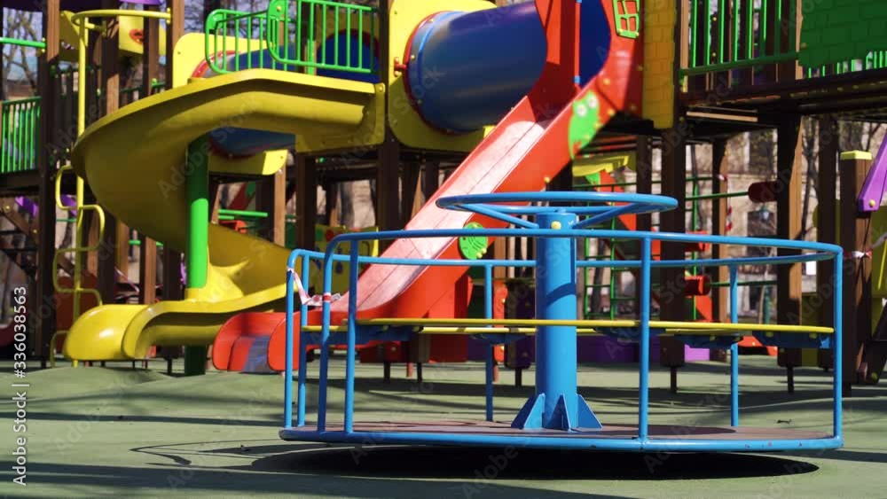 Little carousel with restriction tape on empty playground during coronavirus