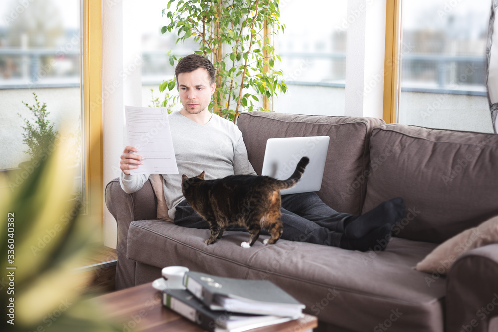Man at home doing paperwork on the sofa