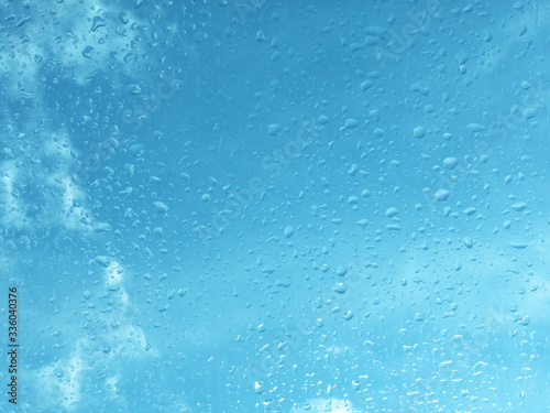 Wet window with rain drops and a cloudy sky outside.