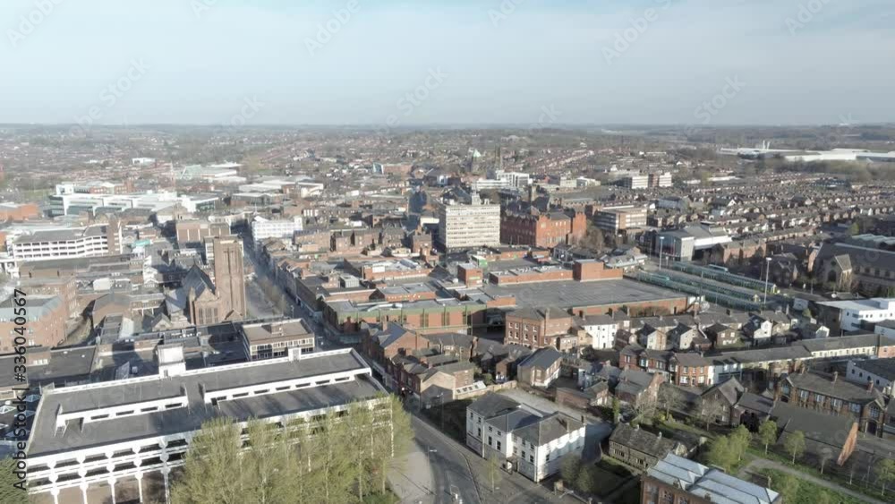 Covid virus suburban town lock down aerial view over quarantined British retail buildings and multi storey car park pull back