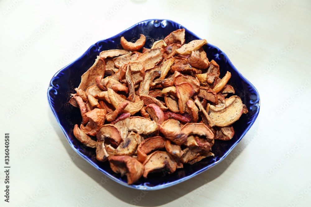 Dehydrated apples chips on plate, top view. Dried Apple chips in a square glass plate . Dried apple slices in woodenl blue plate isolated on white .