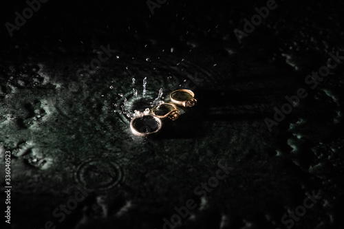 Beautiful wedding rings with water drops on a dark green marble background. wedding concept. love concept