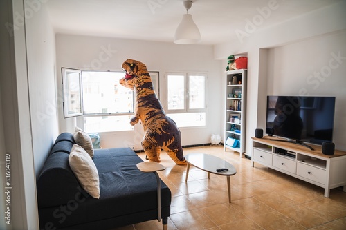 Person disguised as a dinosaur looking through the window in a house photo