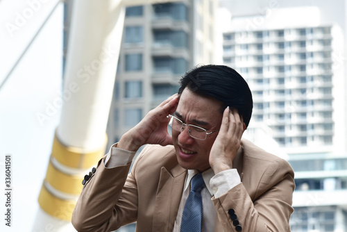 Unpleasant pain. Sad unhappy handsome  business man sitting and holding his forehead while having headache