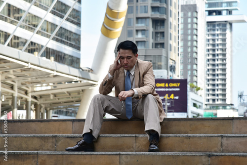 Unpleasant pain. Sad unhappy handsome  business man sitting and holding his forehead while having headache