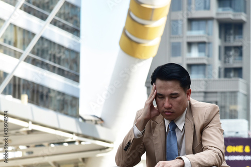 Unpleasant pain. Sad unhappy handsome  business man sitting and holding his forehead while having headache