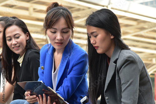Smart young  business woman sitting down  using digital tablet for communication and presentaion with her team