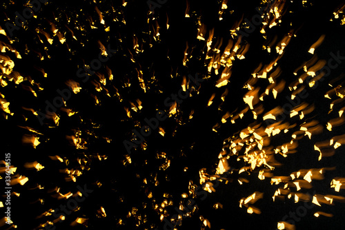 Gold confetti on black background. Flat lay, top view. Long exposure.