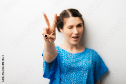 Young woman showing two fingers, positive or peace gesture, on white