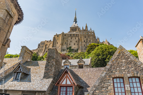 Mont Saint Michel  in France between Bretagne and Normandy, old medieval rock abbey with vegetation and moss on the rocks, tower with a golden figure on top and roofs around. photo