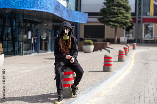 girl in gas mask and black mantle in an empty city