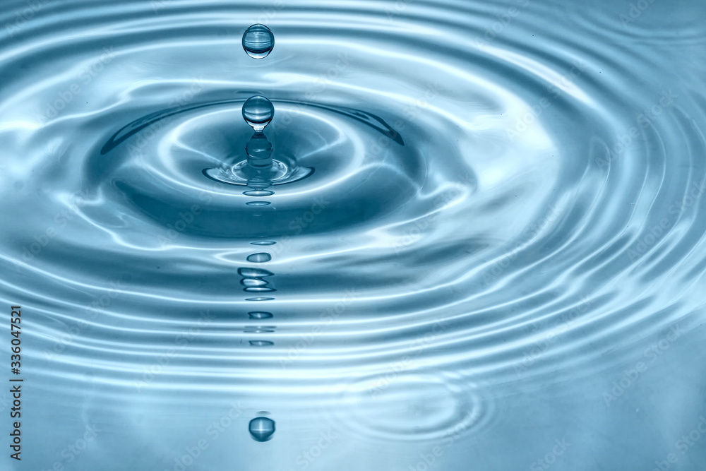 Water drops splash in a glass blue colored Water drops splash in a glass blue colored