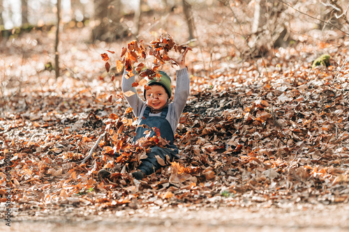Junge spielt im Laub im Wald 3