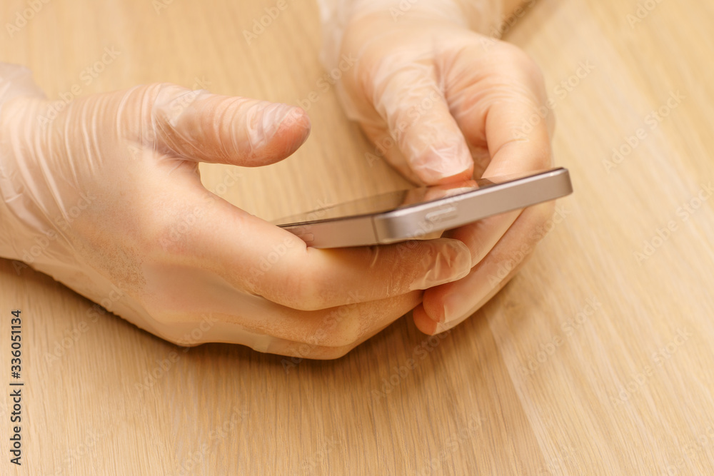 a hands in a protective disposable gloves holding a grey mobile phone a hands in a protective disposable gloves holding a grey mobile phone