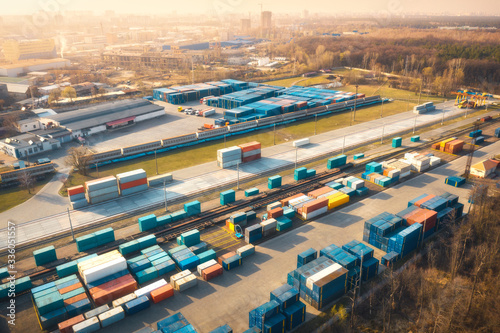Aerial view of container loading and unloading at sunset. Top view of containers at logistics terminal for export and import, train, railroad. Business. Freight transportation on railway. Shipping
