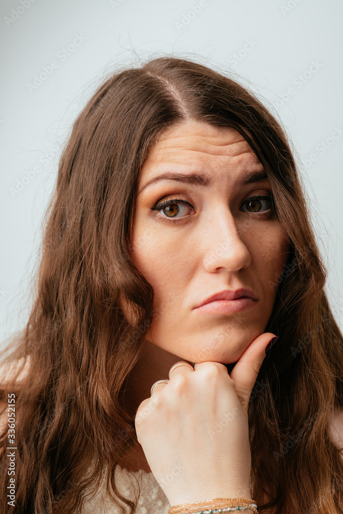 long-haired beautiful young brunette woman holding a fist chin, isolated on a white background long-haired beautiful young brunette woman holding a fist chin, isolated on a white background