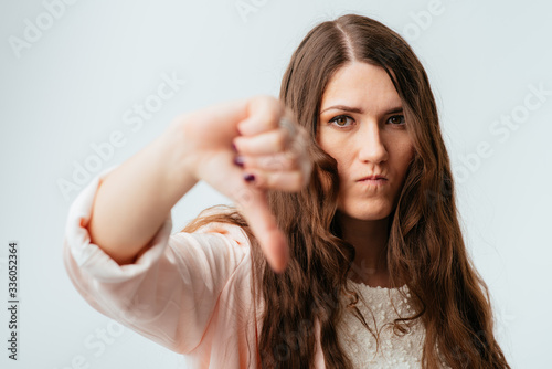 long-haired beautiful brunette girl showing thumb down isolated on white background photo