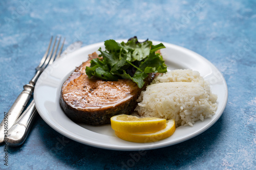 fried salmon with salad, lemon and boiled rice on white plate