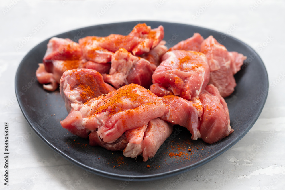 marinated meat on black dish on ceramic background