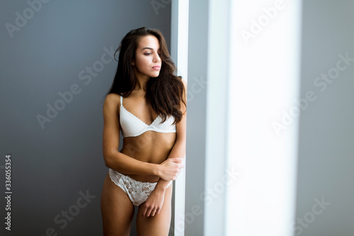 Portrait of sexy woman in lingerie standing by window in bedroom © BGStock72