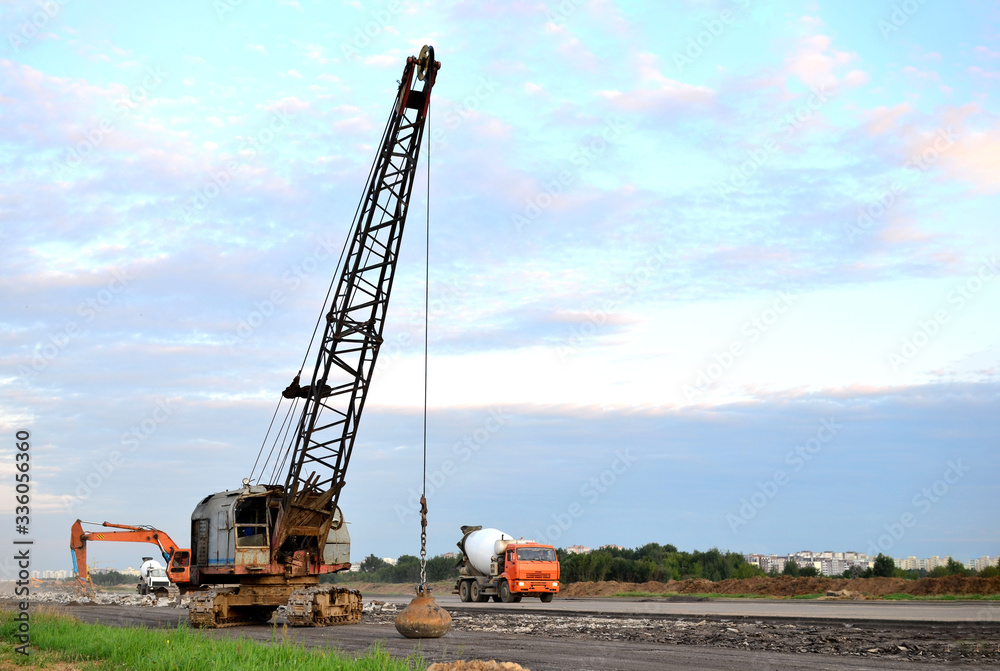 Large crawler crane or dragline excavator with a heavy metal wrecking ball on a steel cable. Wrecking balls at construction sites. Dismantling and demolition of buildings and structures