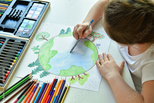 Child girl draws planet for earth day. Protection of enviroment, Save our planet. Concept of art learning and education, love earth , save world and unity.Ecology concept